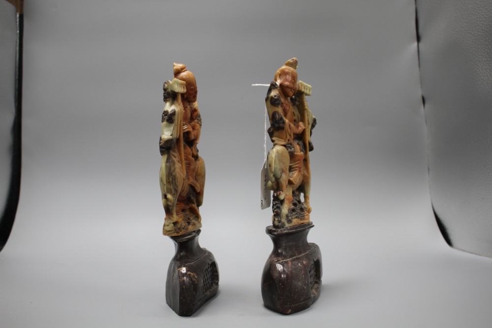 A pair of Chinese soapstone carvings depicting figures riding upon elephants, height 19cm, height with bases 27cm